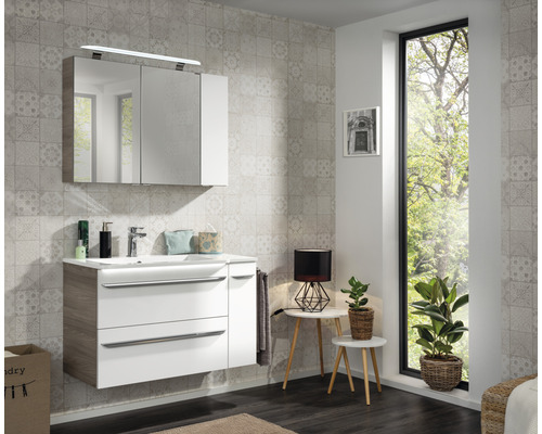 Helles Badezimmer mit Waschtisch, Spiegelschrank und gemusterter Tapete