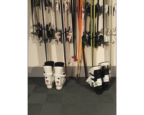 Skischuhe und Skier an einer Wand montiert