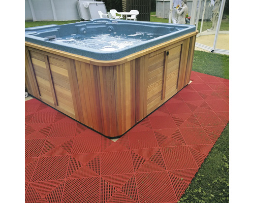 Quadratischer Whirlpool mit Holzverkleidung und rotem Bodenbelag im Garten.