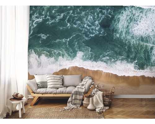 Wohnzimmer mit Fototapete, die eine Küstenlandschaft mit Meer und Sandstrand zeigt.