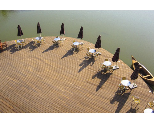 Terrasse am Wasser mit Tischen, Stühlen, Sonnenschirmen und Kanu