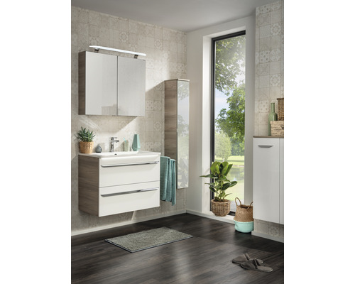 Badezimmer mit Waschtisch, Spiegelschrank, Hochschrank, Handtuch und Zimmerpflanzen für eine helle und freundliche Atmosphäre.