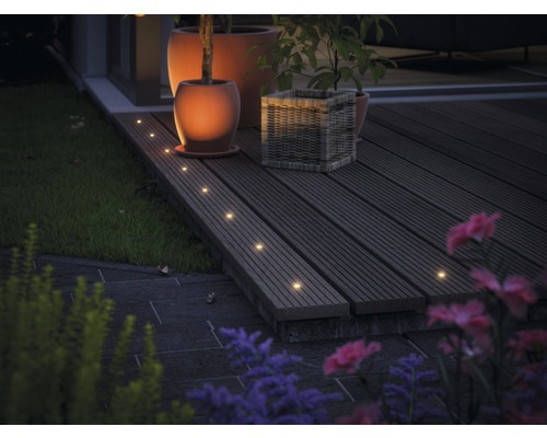 Terrasse mit Holzboden, beleuchtet mit Einbaustrahlern, sowie Blumentöpfen und Pflanzen