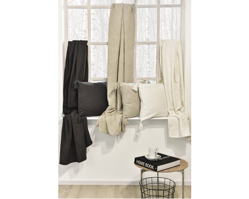 Dekorative Kissen und Decken auf einer Fensterbank mit Tisch und Korb