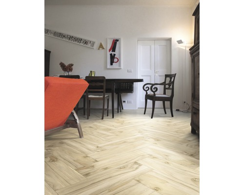 Heller Wohnraum mit Holzboden in Fischgrätmuster, Esstisch und Stühlen.