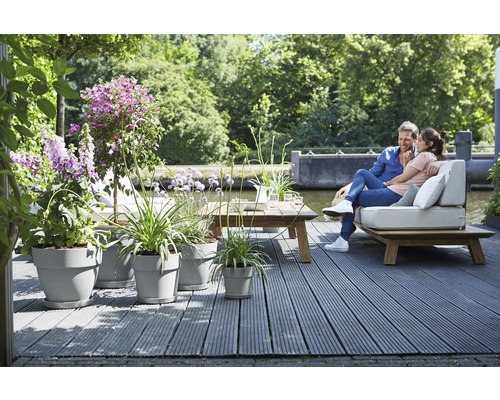 Terrasse mit grauen Blumentöpfen, Holztisch und Paar auf Sitzgelegenheit