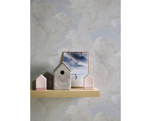 Dekorative Szene mit Holzregal, Dekohäusern und Klemmbrett vor einer Wolken Tapete