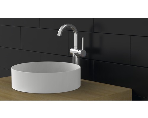 Aufbauwaschbecken mit Armatur auf Waschtischplatte vor dunkler Wand