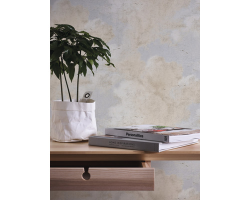 Dekorative Tapete mit Wolkenmuster, kombiniert mit Holztisch, Zimmerpflanze und Büchern.