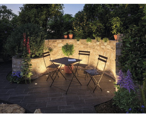 Terrasse mit Natursteinmauer, Tisch und Stühlen sowie integrierter Beleuchtung für den Außenbereich.