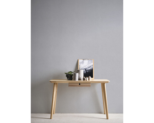 Ein heller Holzschreibtisch mit Schublade, dekoriert mit Pflanze, Behältern und einem Bild.