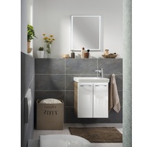 Badezimmer mit Waschtisch, Spiegel, Handtuch und Wäschekorb