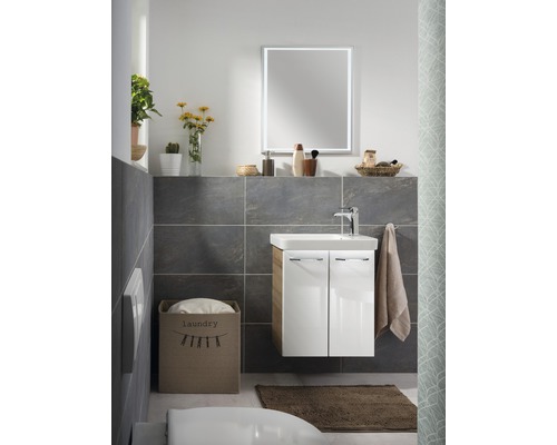Badezimmer mit Waschtisch, Spiegel, Handtuch und Wäschekorb