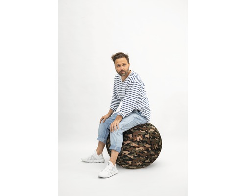 Mann sitzt auf einem Gymnastikball mit Camouflage-Muster