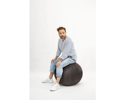 Mann sitzt auf einem Gymnastikball.
