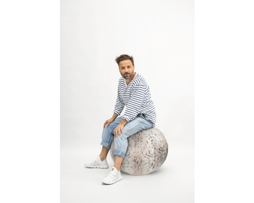 Mann sitzt auf einem Sitzball mit Fellmuster