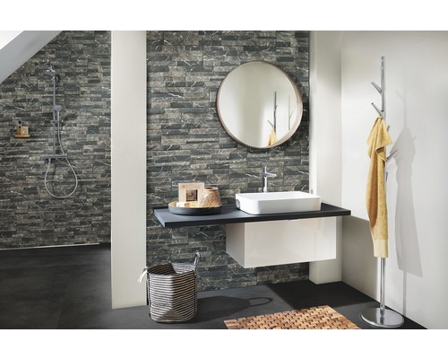 Badezimmer mit Waschtisch, Spiegel, Handtuchhalter und Steinwand