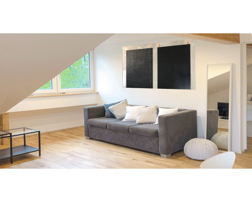 Wohnzimmer mit grauem Sofa, Kissen und minimalistischem Dekor unter einem Dachfenster