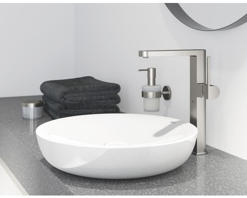 Aufgesetztes Waschbecken mit Armatur, Seifenspender und Handtüchern im Badezimmer