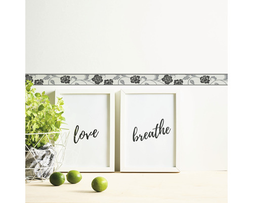 Wandbordüre mit Blumenmuster über zwei gerahmten Bildern mit den Worten Liebe und Atmen.