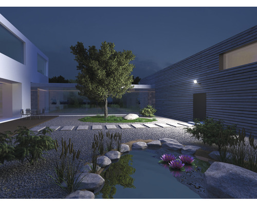 Beleuchteter Garten mit Teich, Steinen, Pflanzen und modernem Haus bei Nacht
