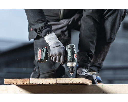 Eine Person bohrt mit einem Akku-Bohrschrauber ein Loch in ein Holzbrett.