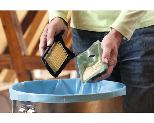 Person entleert Staubsaugerfilter über einem Mülleimer