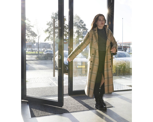 Eingangsmatte vor einer geöffneten Glastür mit Aluminiumrahmen