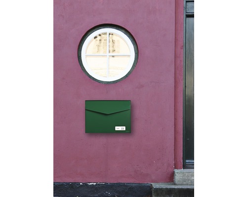 Grüner Briefkasten an einer Hauswand mit runden Fenster