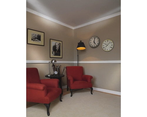 Zwei rote Sessel mit Beistelltisch, Stehlampe und Wanduhren in einem Wohnzimmer