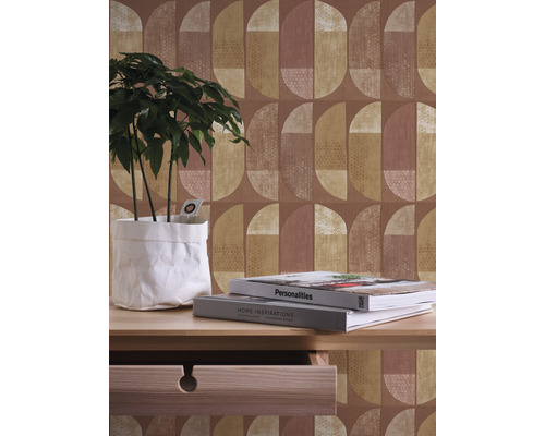 Innenaufnahme mit geometrischer Tapete, Pflanze in Papiertüte und Tisch mit Schublade