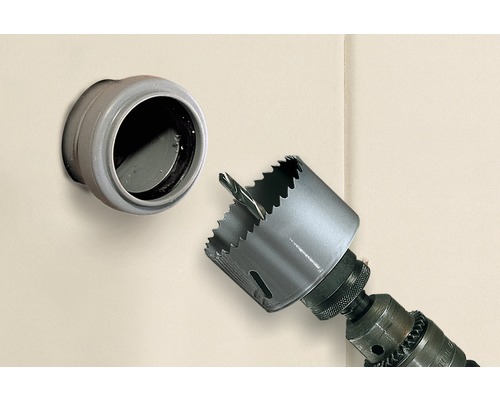 Lochsäge an einer Bohrmaschine neben einer Wanddurchführung