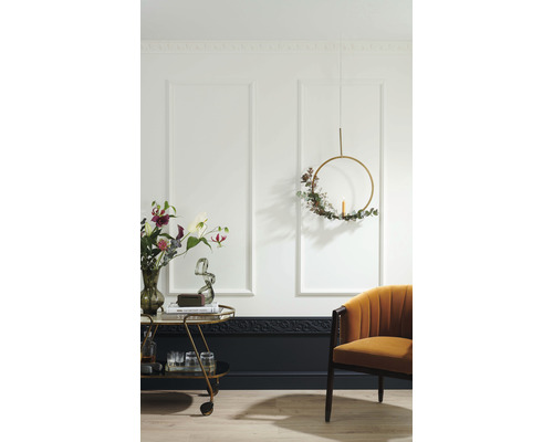 Dekorativer Wohnraum mit Wandpaneelen, Barwagen, Sessel und floralem Akzent