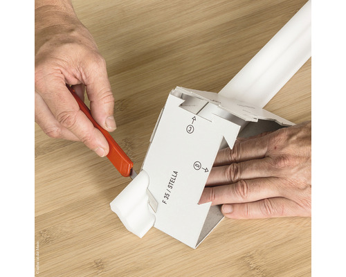 Person schneidet mit einem Cuttermesser ein Verpackungsteil ab.