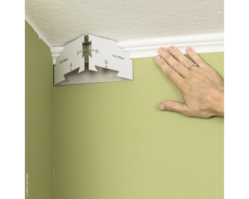 Eckmontagehilfe für Zierleisten und eine Hand an einer Wand