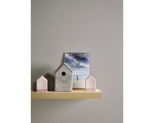 Dekorative Häuser aus Beton und Holz auf einem Regal, mit einem Klemmbrett im Hintergrund.