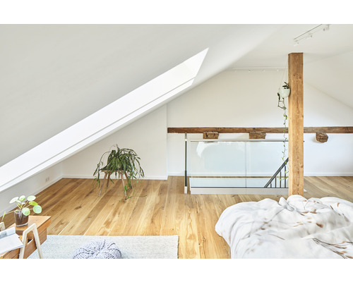 Helles Schlafzimmer im Dachgeschoss mit Dachfenster, Holzbalken und Holzboden