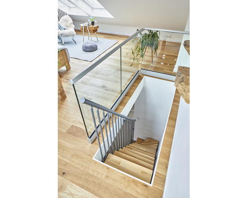 Innenansicht eines Hauses mit einer Holztreppe, einem Glasgeländer und einer hellen Einrichtung.