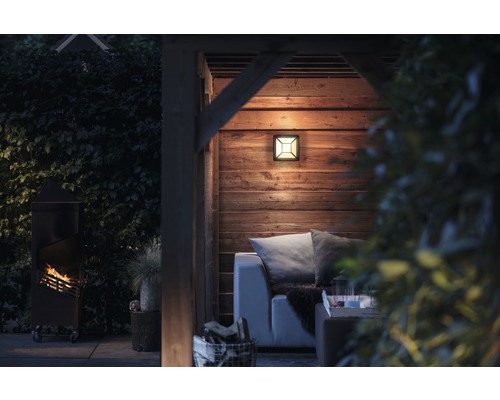 Beleuchteter Außenbereich mit Lampe, Holzofen und Sitzgelegenheit