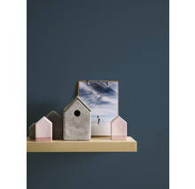 Dekorative Häuser aus Beton und Holz auf einem Regal, zusammen mit einem Bild auf einem Klemmbrett.