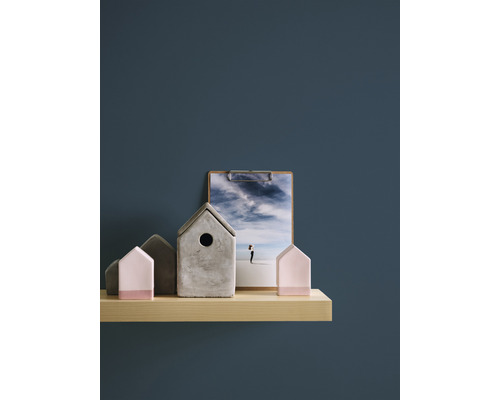 Dekorative Häuser aus Beton und Holz auf einem Regal, zusammen mit einem Bild auf einem Klemmbrett.