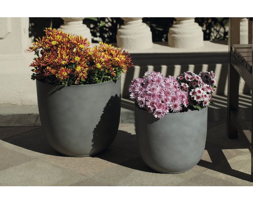 Zwei graue Pflanzgefäße mit bunten Blumenarrangements im Freien.