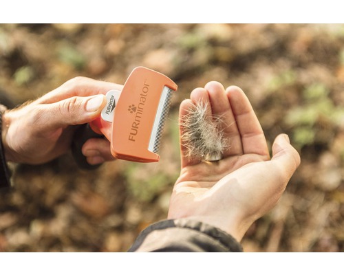 Person hält FURminator Fellpflegekamm und Fell in der Hand