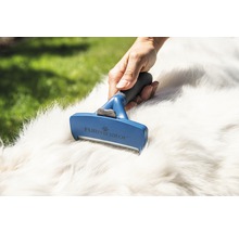 Eine Hand benutzt eine FURminator Fellbürste auf dem Fell eines Hundes.