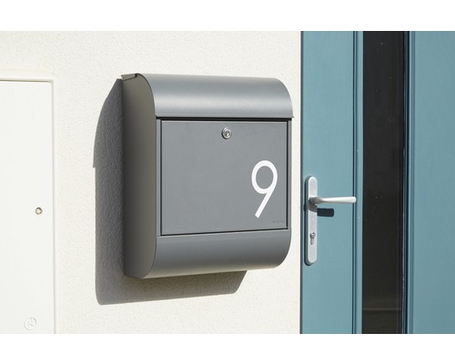 Grauer Briefkasten mit Hausnummer 9 an einer Wand montiert
