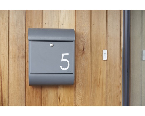 Grauer Briefkasten mit der Nummer 5 an einer Holzwand