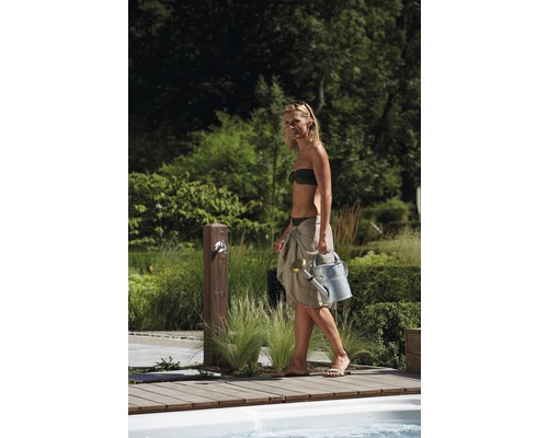 Frau mit Gießkanne in einem Garten mit Wasserhahn