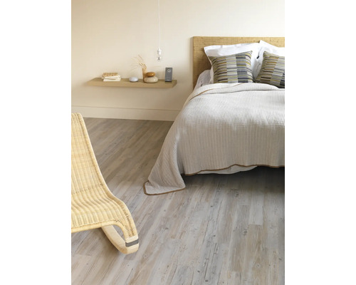 Schlafzimmer mit Bett, Nachttisch und Korbsessel auf Holzboden