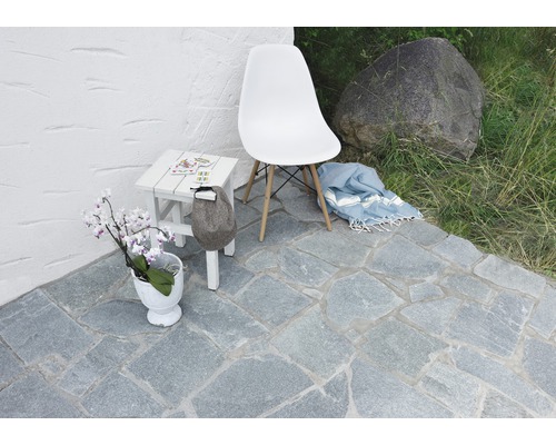 Außenbereich mit Natursteinpflaster, Stuhl, Tisch und Dekoration
