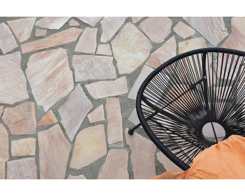 Terrasse mit Polygonalplatten und schwarzem Rattansessel